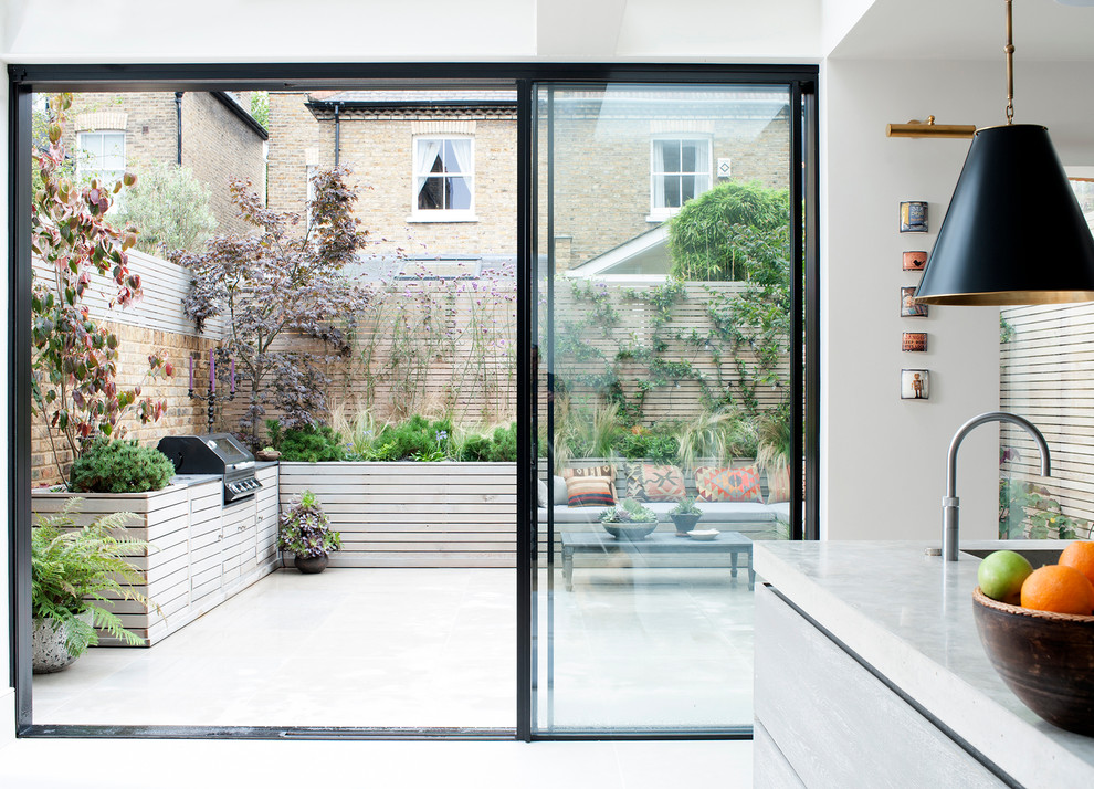 Design ideas for an eclectic backyard partial sun garden for summer in London with a container garden and natural stone pavers.