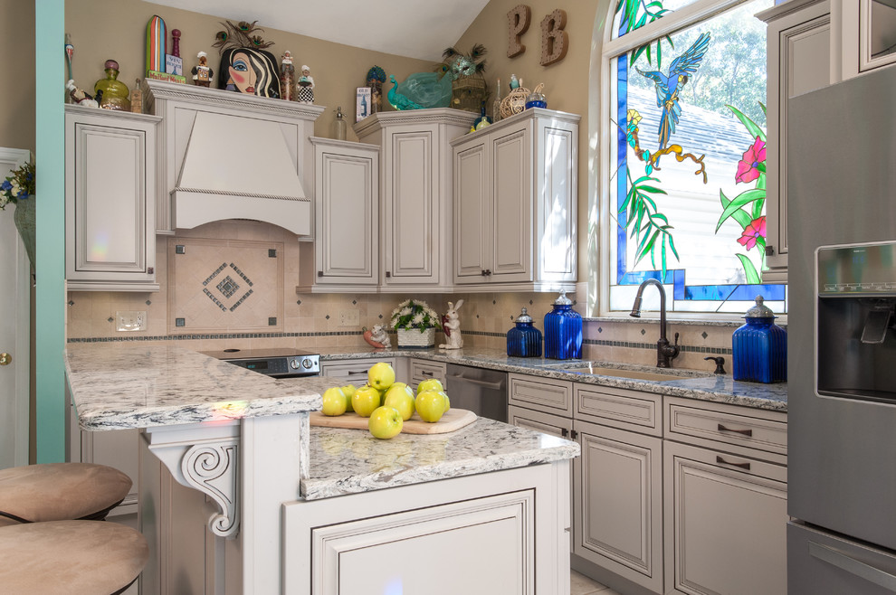 Traditional l-shaped kitchen in St Louis with an undermount sink, raised-panel cabinets, grey cabinets, beige splashback, stone tile splashback, stainless steel appliances, with island and granite benchtops.