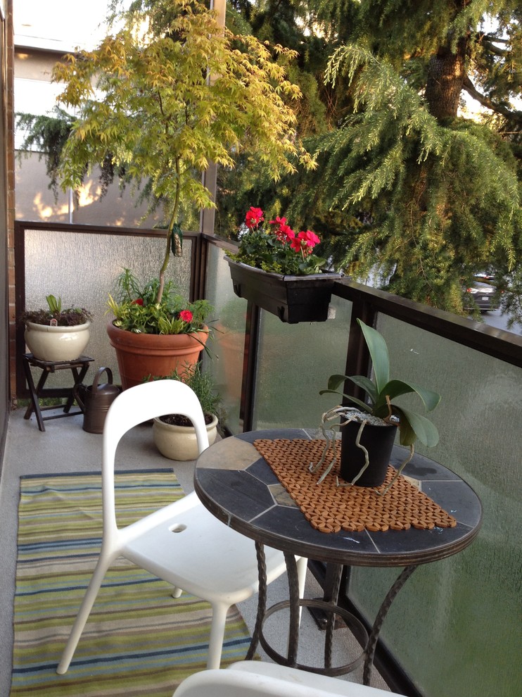 This is an example of a small modern front yard verandah in Vancouver with a container garden and a roof extension.