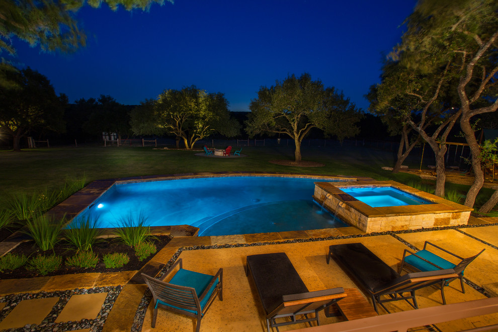 Inspiration for a mid-sized traditional backyard custom-shaped lap pool in Austin with a water feature and concrete slab.