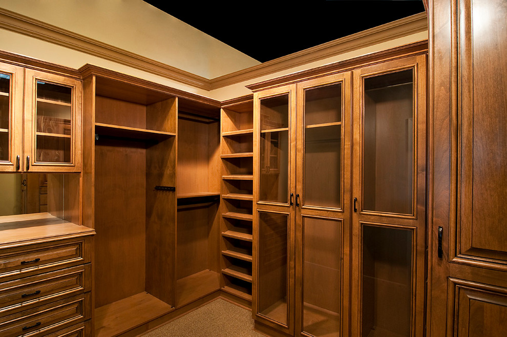 Photo of a mid-sized traditional gender-neutral walk-in wardrobe in Denver with raised-panel cabinets, dark wood cabinets, carpet and brown floor.