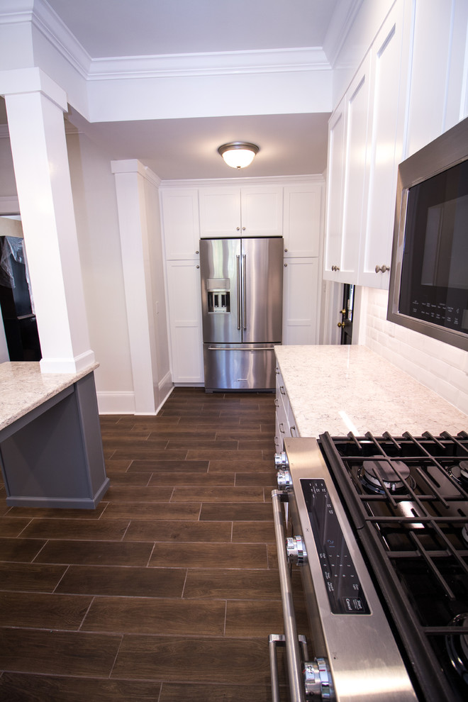 Eat-in kitchen - small u-shaped ceramic tile eat-in kitchen idea with an undermount sink, shaker cabinets, white cabinets, quartz countertops, white backsplash, subway tile backsplash, stainless steel appliances, an island and white countertops
