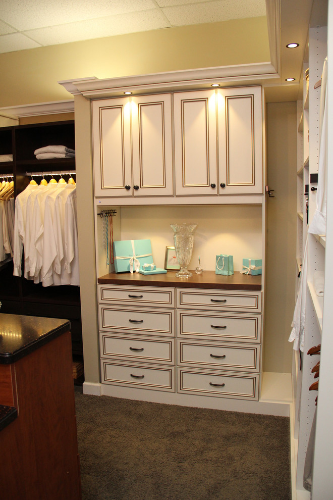 This is an example of a traditional gender-neutral walk-in wardrobe in Tampa with recessed-panel cabinets, brown cabinets and carpet.
