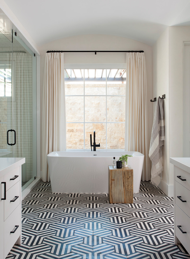 Inspiration for a mediterranean master bathroom in Houston with flat-panel cabinets, white cabinets, a freestanding tub, multi-coloured floor, a hinged shower door, white benchtops, a built-in vanity and vaulted.