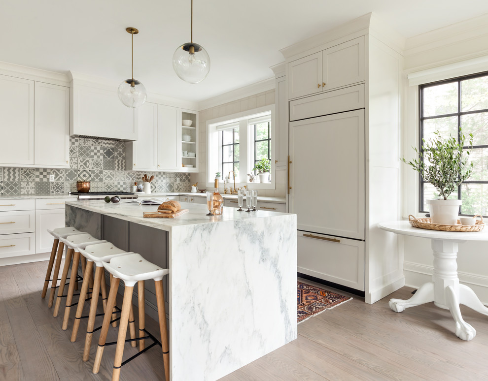 Design ideas for a transitional l-shaped kitchen in New York with an undermount sink, shaker cabinets, white cabinets, grey splashback, cement tile splashback, panelled appliances, light hardwood floors, with island and beige floor.