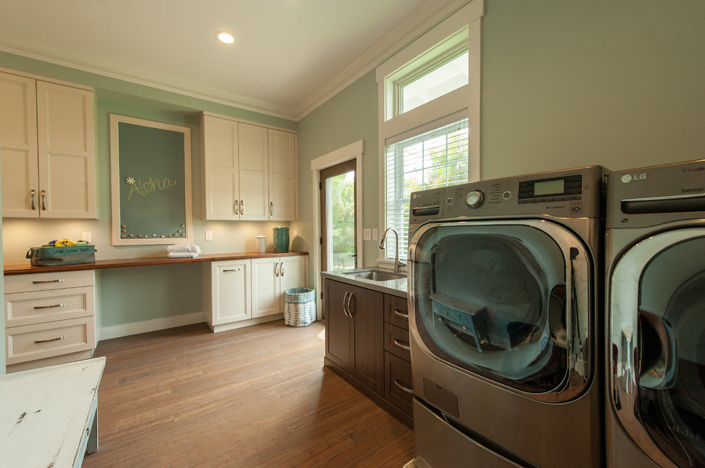 This is an example of a mid-sized transitional utility room in Hawaii with an undermount sink, white cabinets, wood benchtops, green walls, bamboo floors and a side-by-side washer and dryer.