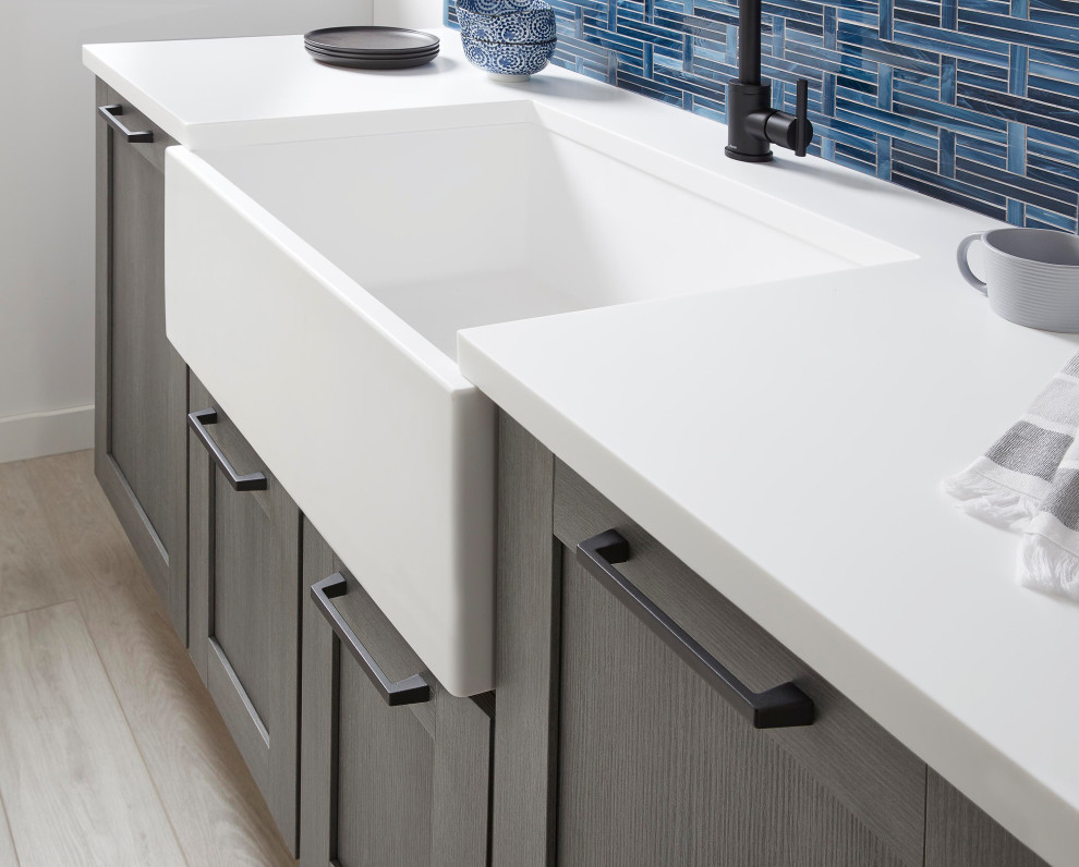 Trendy light wood floor and beige floor eat-in kitchen photo in Austin with a farmhouse sink, shaker cabinets, solid surface countertops, blue backsplash, no island and white countertops