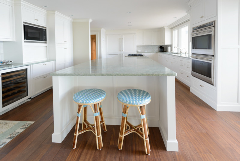 Inspiration for a transitional medium tone wood floor kitchen remodel in Boston with a triple-bowl sink, recessed-panel cabinets, white cabinets, granite countertops, white backsplash, mosaic tile backsplash, stainless steel appliances and an island