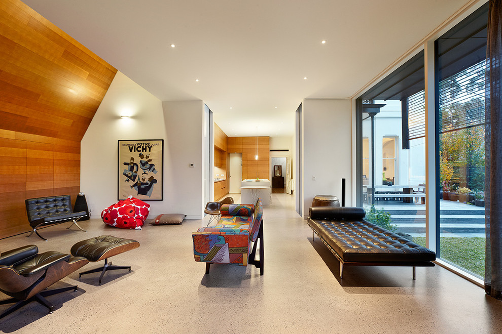 This is an example of a contemporary living room in Melbourne with white walls and concrete floors.