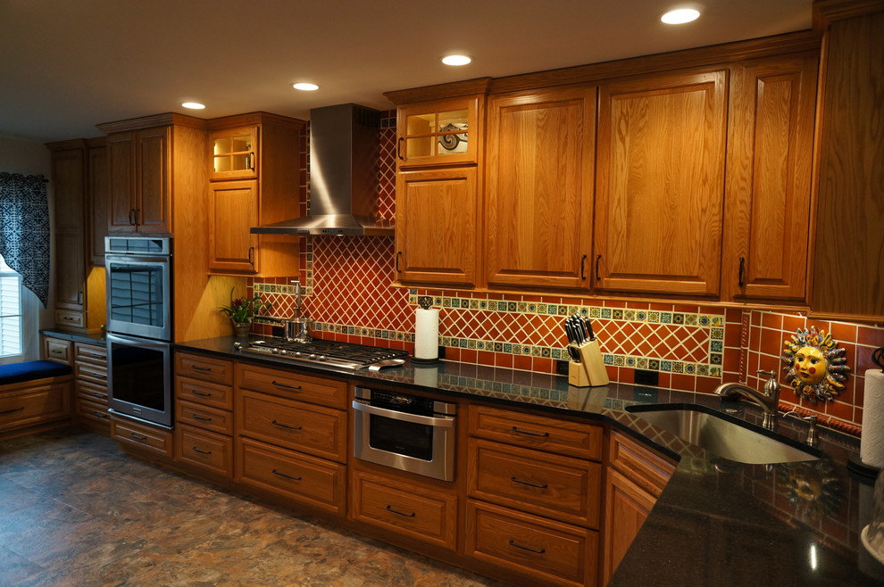 Inspiration for a small l-shaped eat-in kitchen in Philadelphia with an undermount sink, raised-panel cabinets, medium wood cabinets, quartz benchtops, brown splashback, terra-cotta splashback, stainless steel appliances, linoleum floors and no island.