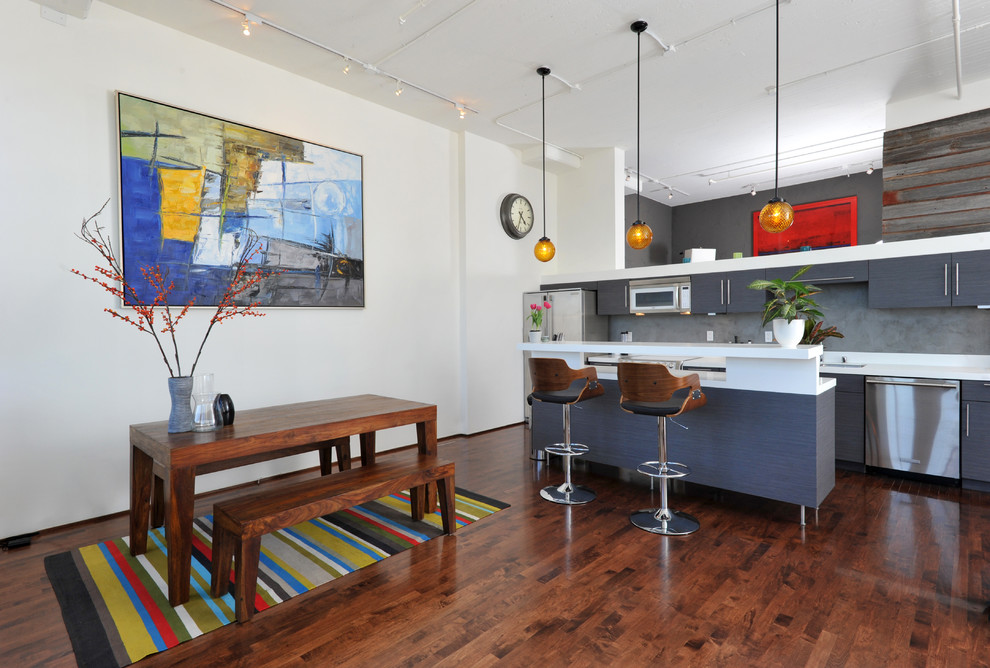 This is an example of an industrial kitchen/dining combo in San Francisco with white walls and dark hardwood floors.