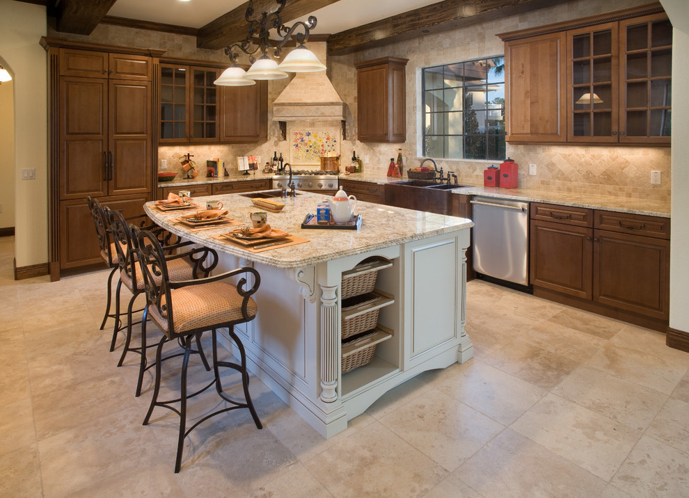 Photo of a large mediterranean l-shaped kitchen in Detroit with a farmhouse sink, raised-panel cabinets, medium wood cabinets, granite benchtops, beige splashback, ceramic splashback, panelled appliances, ceramic floors, with island and beige floor.