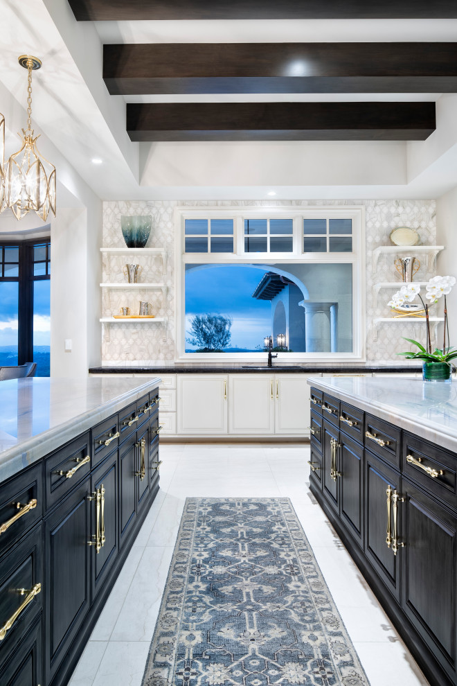 This is an example of an expansive transitional u-shaped open plan kitchen in Austin with an undermount sink, raised-panel cabinets, black cabinets, quartz benchtops, grey splashback, mosaic tile splashback, panelled appliances, marble floors, multiple islands, white floor, white benchtop and exposed beam.