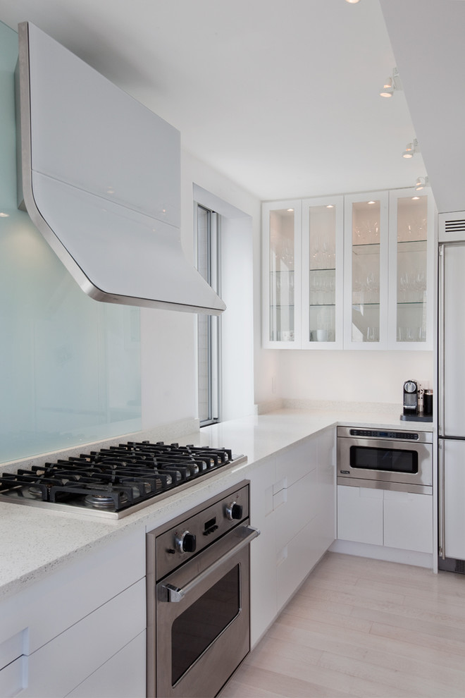 This is an example of a modern kitchen in New York with white cabinets and flat-panel cabinets.