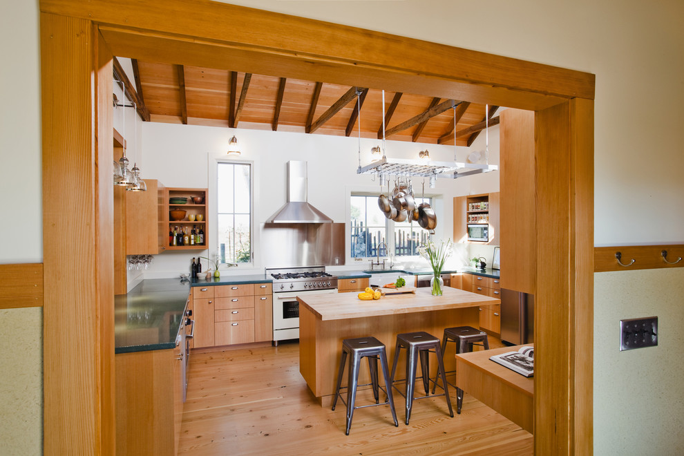 Photo of a country u-shaped eat-in kitchen in San Francisco with stainless steel appliances, a farmhouse sink, medium wood cabinets, metallic splashback, light hardwood floors and with island.