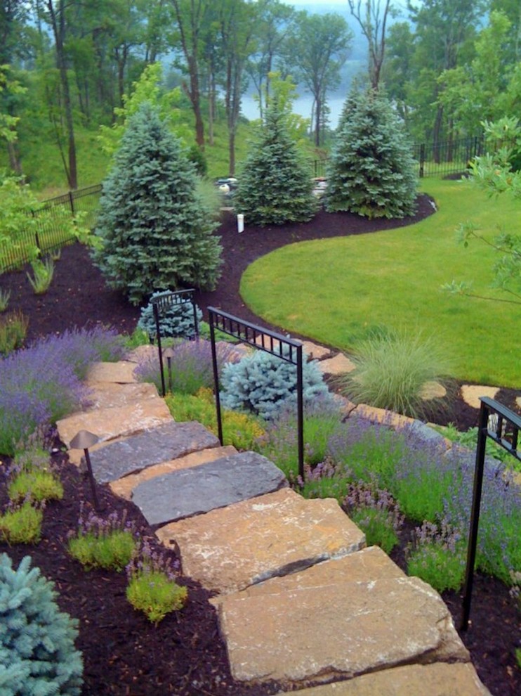 This is an example of a mid-sized transitional full sun backyard stone landscaping in Cincinnati for spring.