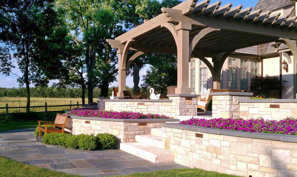 Design ideas for a traditional backyard garden in Chicago with natural stone pavers and a retaining wall.