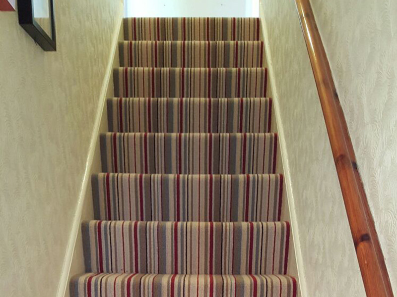 Mid-sized transitional carpeted u-shaped staircase in London with carpet risers.