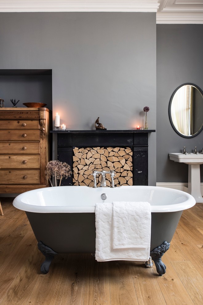 Design ideas for a large traditional master bathroom in London with a pedestal sink, a claw-foot tub, grey walls and medium hardwood floors.