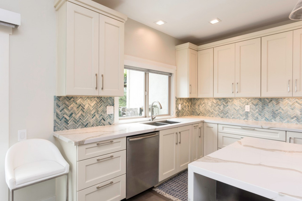 Large transitional l-shaped dark wood floor eat-in kitchen photo with an undermount sink, shaker cabinets, white cabinets, quartz countertops, blue backsplash, glass tile backsplash, stainless steel appliances, an island and white countertops