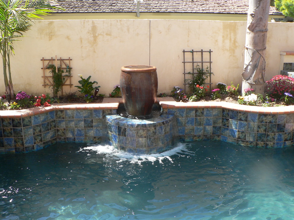 Inspiration for a small mediterranean backyard custom-shaped lap pool in Orange County with tile and a hot tub.