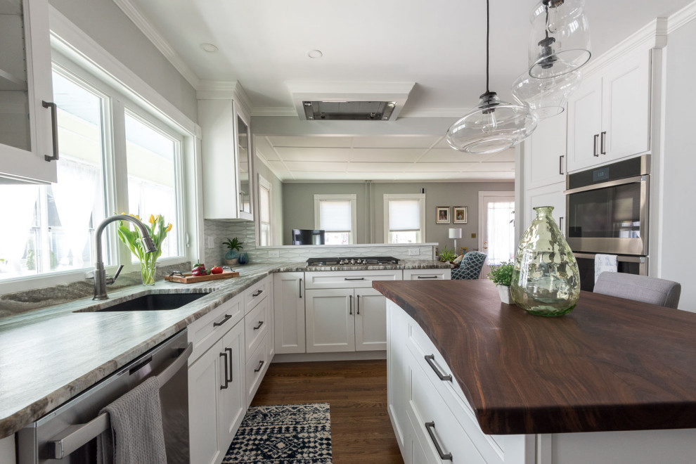 Example of a mid-sized transitional u-shaped medium tone wood floor and brown floor eat-in kitchen design in Boston with an undermount sink, shaker cabinets, white cabinets, quartzite countertops, gray backsplash, ceramic backsplash, stainless steel appliances, an island and multicolored countertops