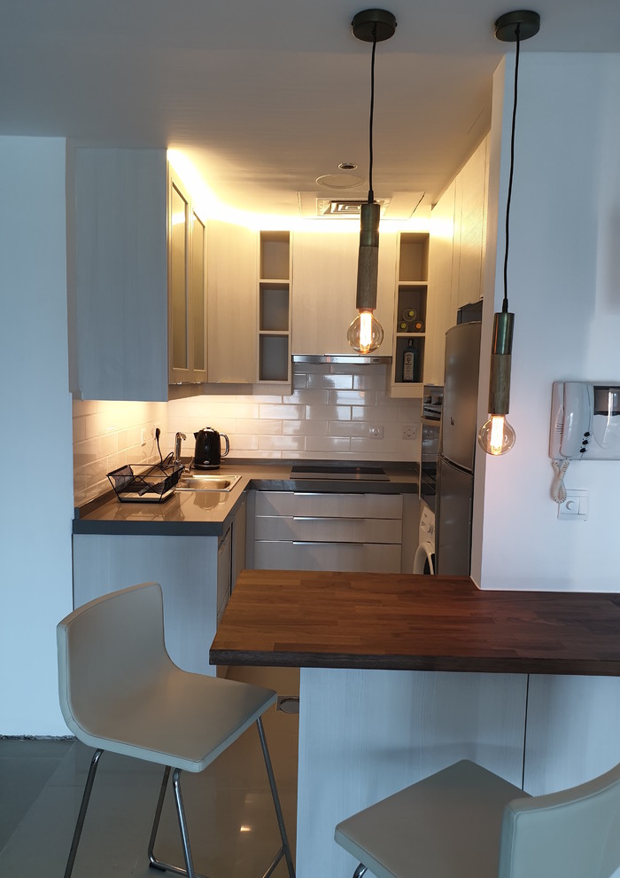 Example of a small minimalist u-shaped kitchen pantry design with a single-bowl sink, flat-panel cabinets, white cabinets, granite countertops, white backsplash, subway tile backsplash, stainless steel appliances and gray countertops