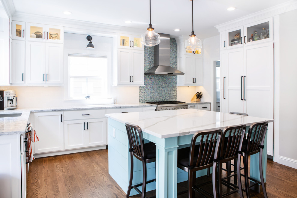 Mid-sized transitional l-shaped eat-in kitchen in Denver with an undermount sink, shaker cabinets, white cabinets, quartzite benchtops, white splashback, subway tile splashback, stainless steel appliances, medium hardwood floors, with island, brown floor and white benchtop.