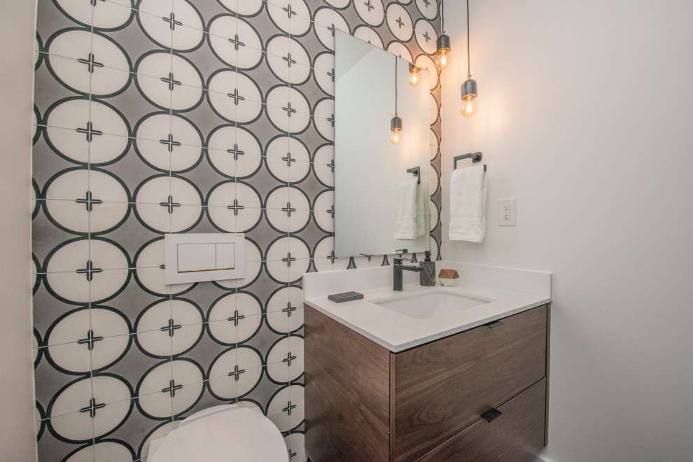 This is an example of a small midcentury powder room in Los Angeles with flat-panel cabinets, medium wood cabinets, a wall-mount toilet, black and white tile, cement tile, white walls, an undermount sink, engineered quartz benchtops, white benchtops and a floating vanity.