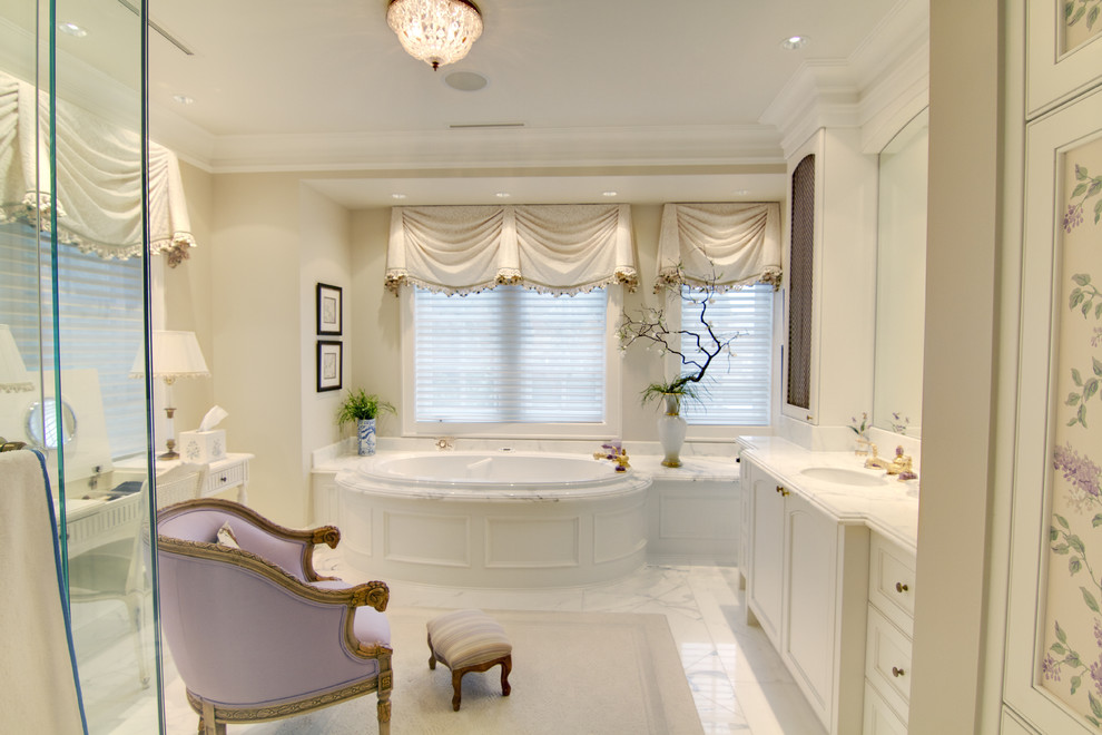 This is an example of a traditional bathroom in Vancouver with an undermount sink, recessed-panel cabinets, a drop-in tub and white tile.