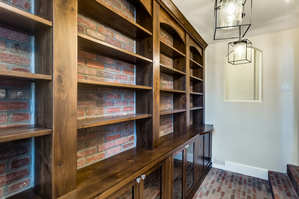 Photo of a large traditional gender-neutral walk-in wardrobe in Denver with shaker cabinets, medium wood cabinets and brick floors.
