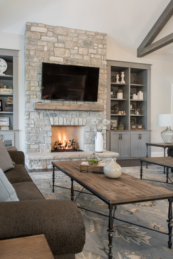 Inspiration for a traditional open concept living room in St Louis with beige walls, dark hardwood floors, a standard fireplace, a stone fireplace surround, a wall-mounted tv and brown floor.