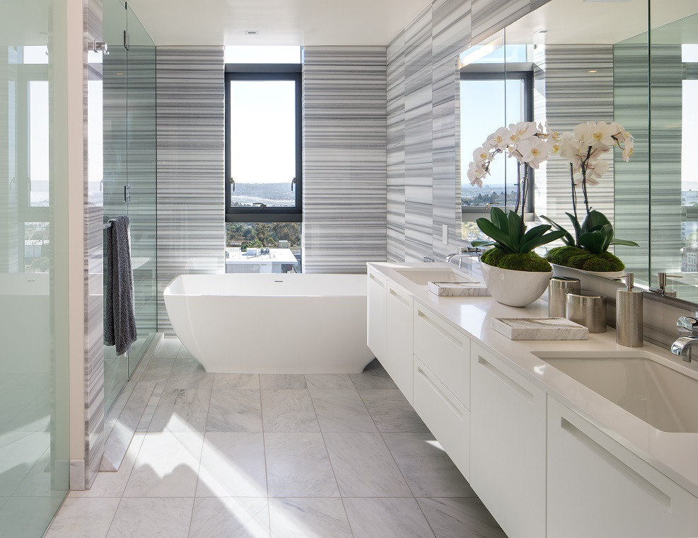 This is an example of a large contemporary master bathroom in San Diego with flat-panel cabinets, white cabinets, a freestanding tub, a curbless shower, a one-piece toilet, multi-coloured tile, glass sheet wall, multi-coloured walls, ceramic floors, an undermount sink, granite benchtops, beige floor, a hinged shower door, white benchtops, a double vanity and a floating vanity.