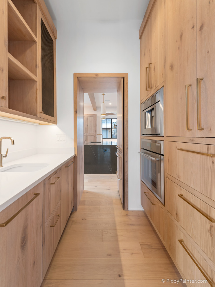 Open concept kitchen - large transitional u-shaped light wood floor and brown floor open concept kitchen idea in Chicago with an undermount sink, flat-panel cabinets, white cabinets, quartz countertops, white backsplash, porcelain backsplash, colored appliances, an island and black countertops
