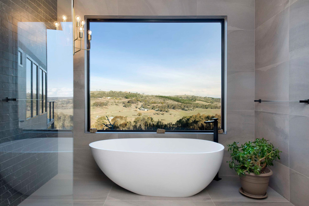 Design ideas for a small contemporary master bathroom in Canberra - Queanbeyan with flat-panel cabinets, medium wood cabinets, a freestanding tub, an open shower, a one-piece toilet, gray tile, subway tile, grey walls, ceramic floors, a drop-in sink, wood benchtops, grey floor, an open shower and white benchtops.