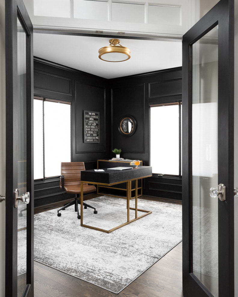 Ejemplo de despacho clásico renovado grande con paredes negras, suelo de madera oscura, chimenea de doble cara, marco de chimenea de piedra, escritorio independiente y boiserie
