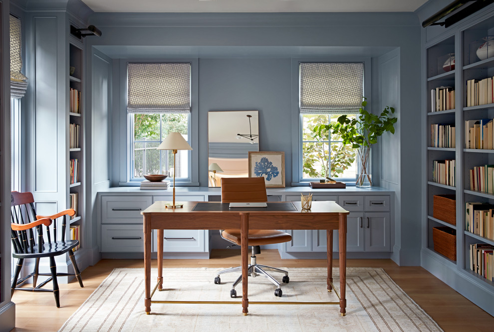 Klassisches Arbeitszimmer mit blauer Wandfarbe, braunem Holzboden, freistehendem Schreibtisch und braunem Boden in Houston