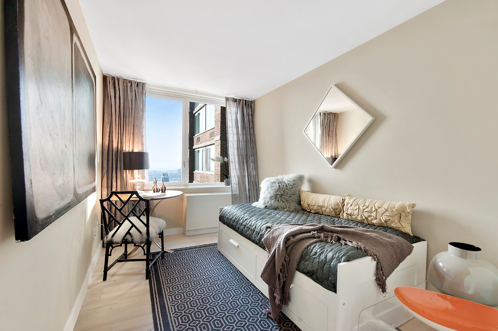This is an example of a contemporary guest bedroom in New York with beige walls and light hardwood floors.