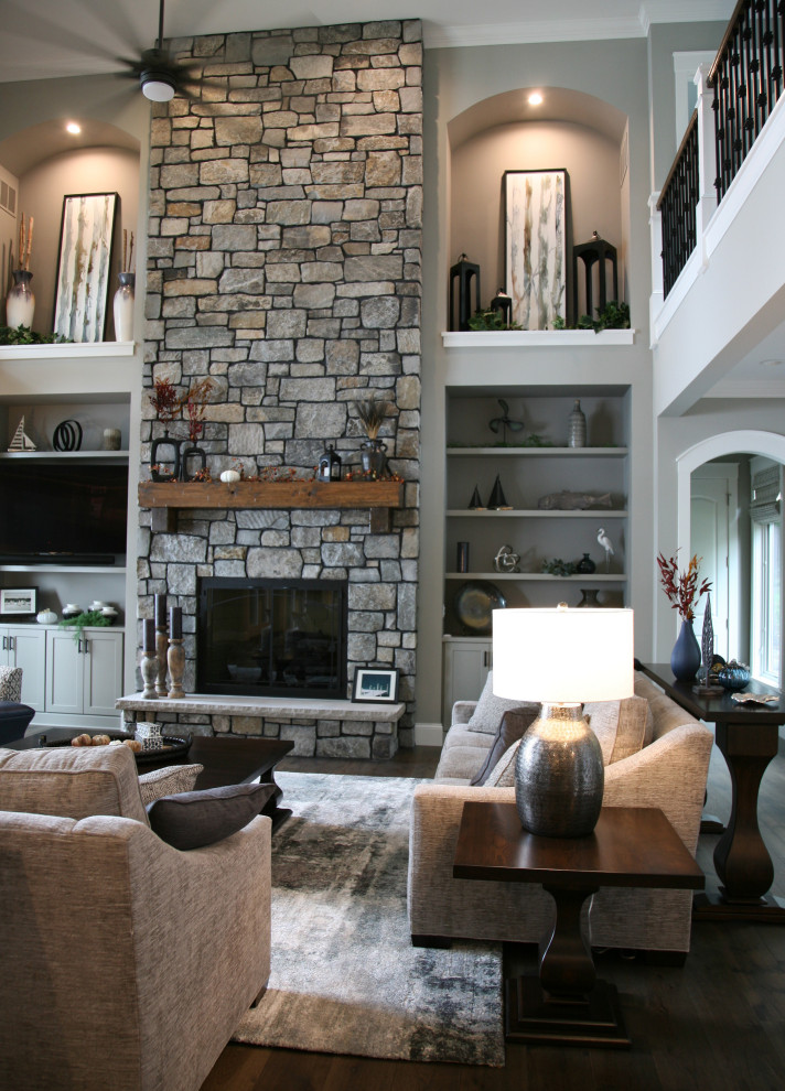 Inspiration for a huge timeless open concept medium tone wood floor, brown floor and vaulted ceiling living room remodel in Milwaukee with gray walls, a standard fireplace, a stone fireplace and a media wall