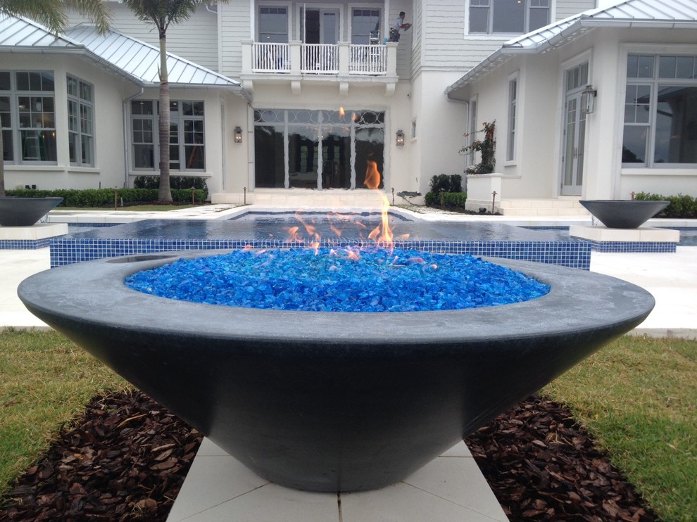 This is an example of a large beach style backyard rectangular pool in Orlando with natural stone pavers and a hot tub.