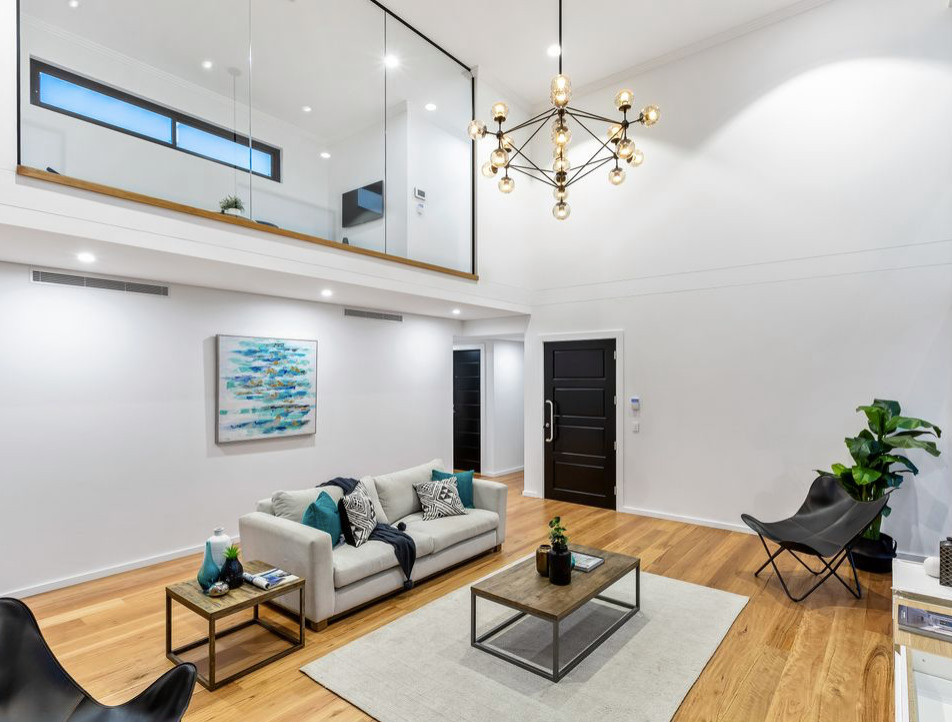 Photo of a large open concept living room in Sydney with white walls, light hardwood floors, a wall-mounted tv and brown floor.