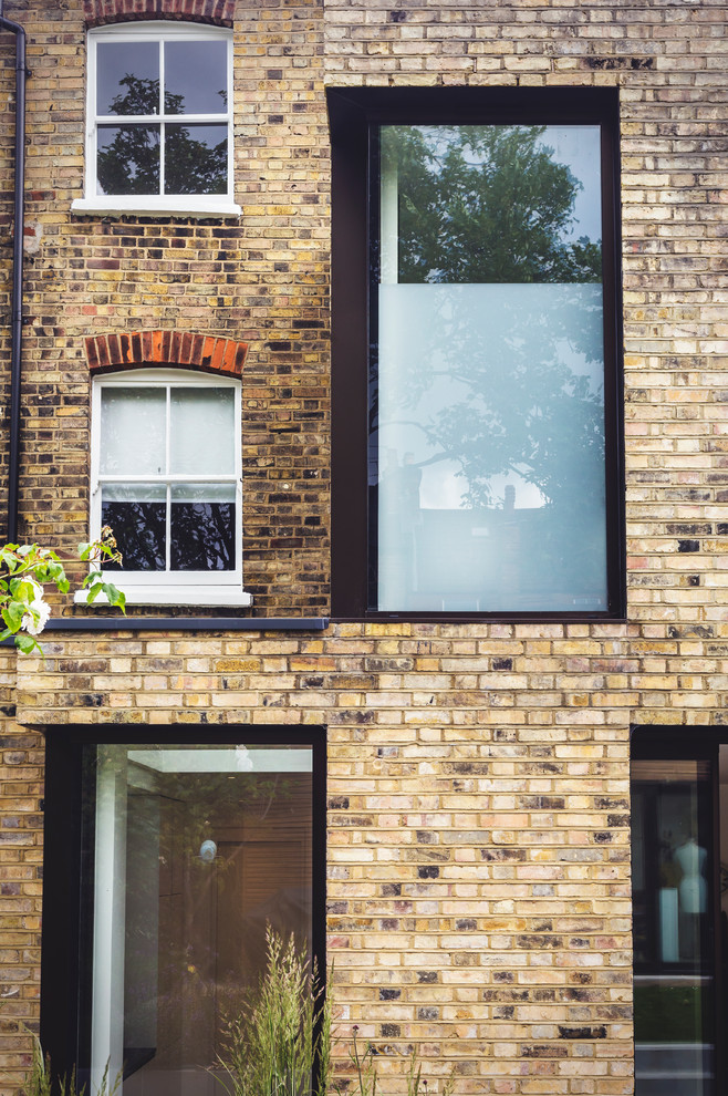 Inspiration for a mid-sized contemporary two-storey brick yellow townhouse exterior in London.
