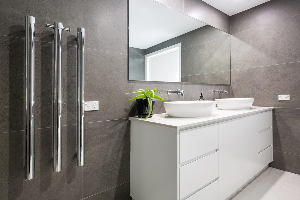 Inspiration for a large contemporary master bathroom in Sydney with flat-panel cabinets, white cabinets, a freestanding tub, a corner shower, a wall-mount toilet, brown tile, porcelain tile, brown walls, porcelain floors, a vessel sink, engineered quartz benchtops, beige floor, a hinged shower door and white benchtops.