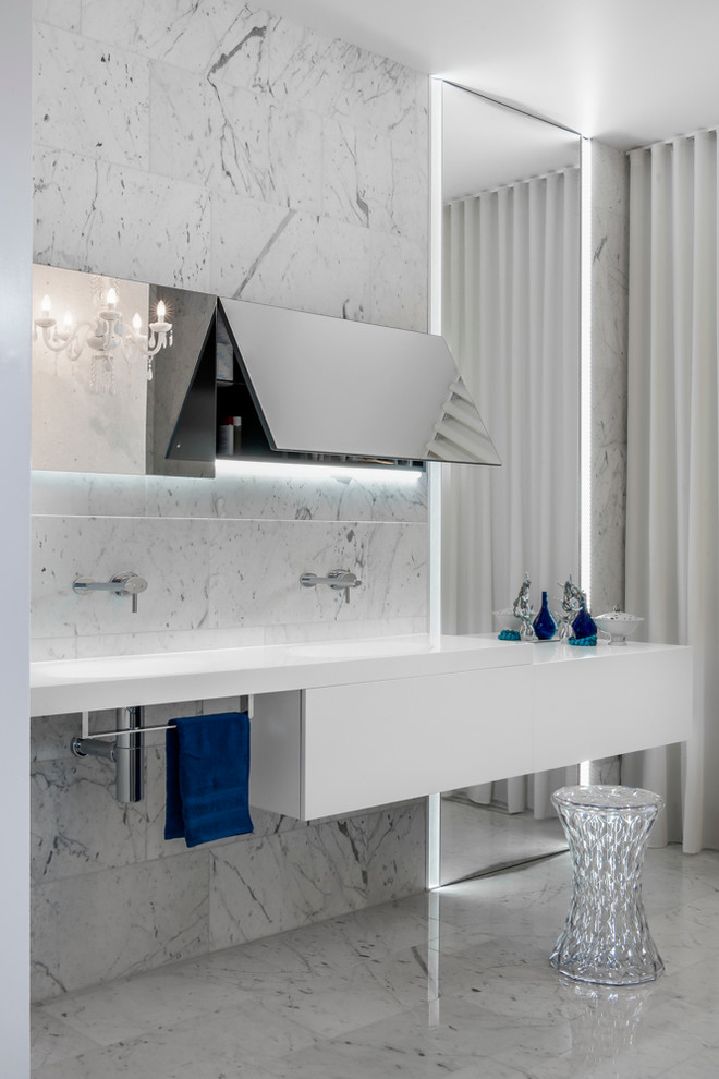 Photo of a mid-sized modern master bathroom in Sydney with an integrated sink, flat-panel cabinets, white cabinets, solid surface benchtops, a freestanding tub, an open shower, a wall-mount toilet, white tile, stone tile, white walls and marble floors.