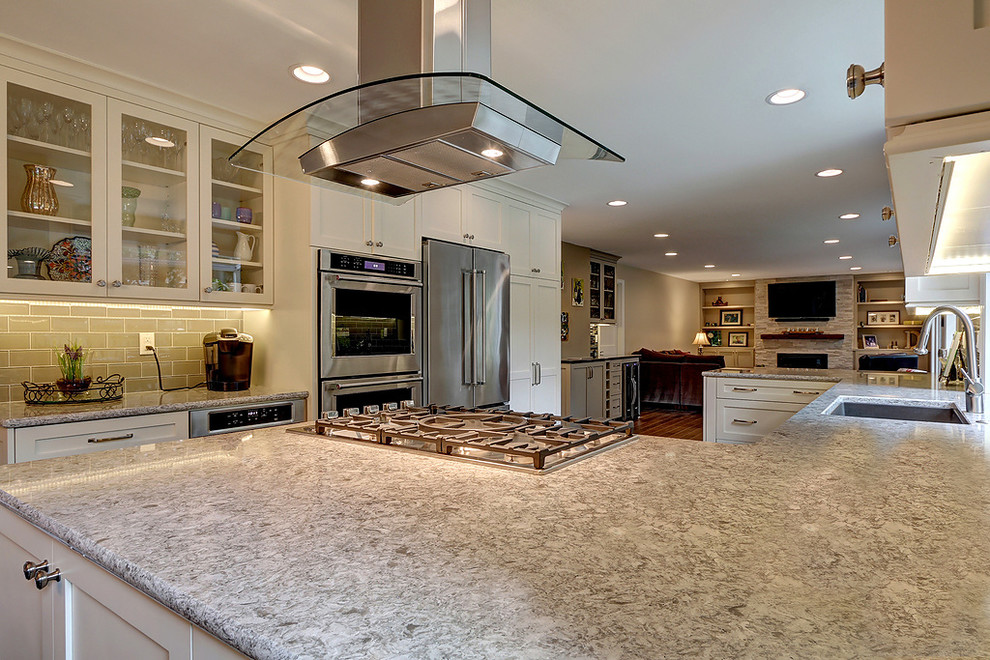 Example of a large transitional u-shaped dark wood floor and brown floor open concept kitchen design in Seattle with an undermount sink, shaker cabinets, white cabinets, quartz countertops, gray backsplash, glass tile backsplash, stainless steel appliances and a peninsula