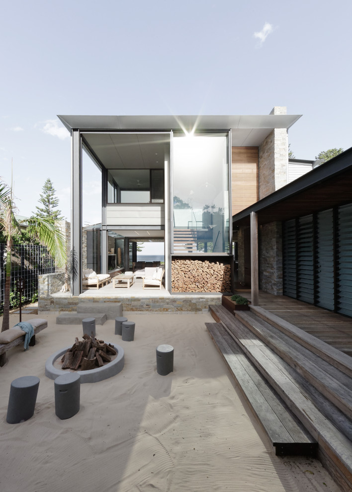 Design ideas for a mid-sized modern side yard deck in Central Coast with a fire feature and a roof extension.