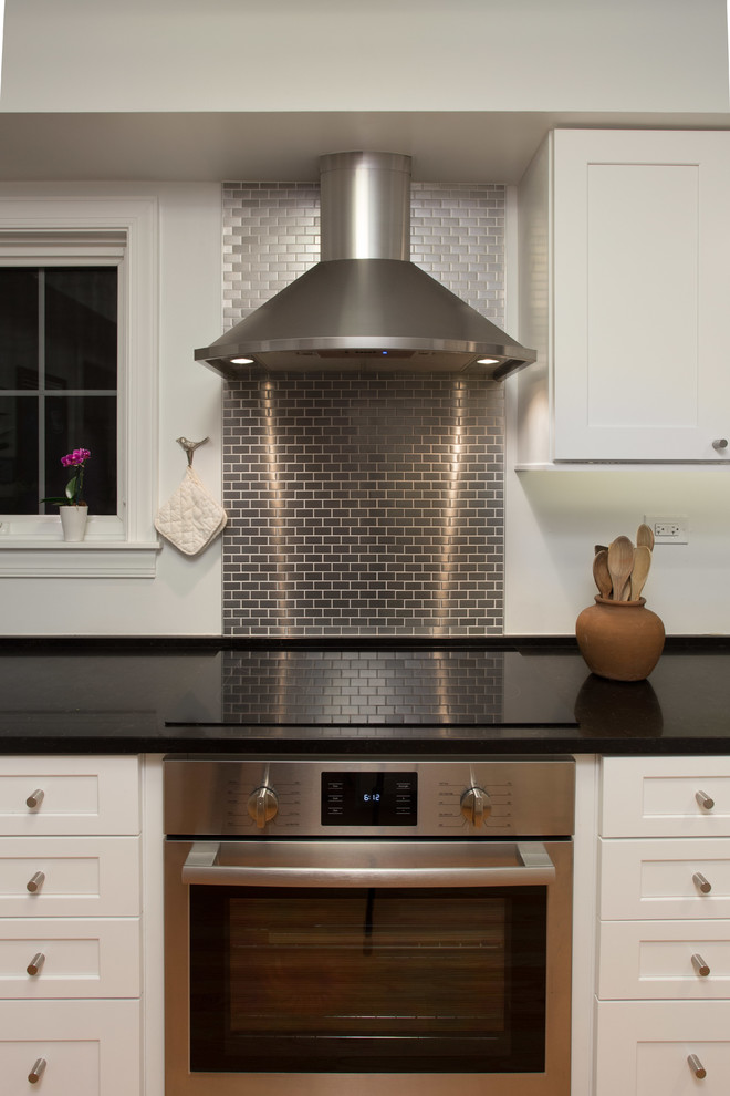 Inspiration for a mid-sized transitional u-shaped medium tone wood floor enclosed kitchen remodel in Chicago with a double-bowl sink, white cabinets, quartzite countertops, gray backsplash, subway tile backsplash, stainless steel appliances, no island and shaker cabinets