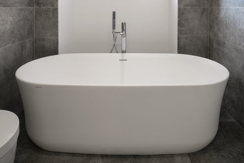 Inspiration for a large contemporary master bathroom in Rome with open cabinets, grey cabinets, a freestanding tub, a wall-mount toilet, gray tile, porcelain tile, grey walls, porcelain floors, a vessel sink, limestone benchtops and grey floor.