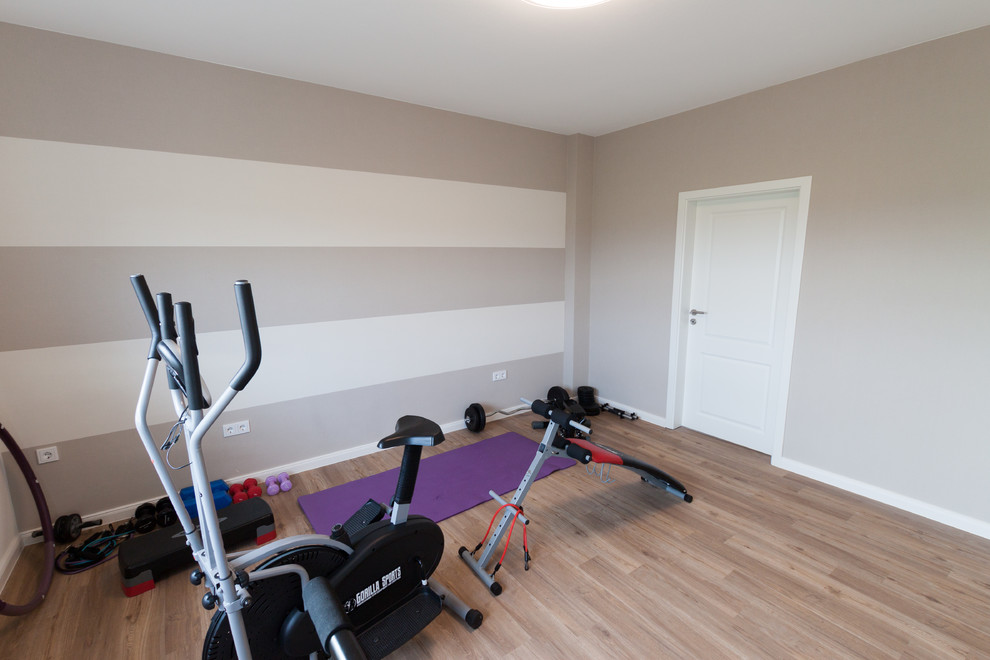 Mid-sized contemporary multipurpose gym in Bremen with beige walls, vinyl floors and brown floor.