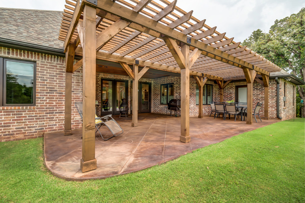 Design ideas for a mid-sized arts and crafts backyard patio in Oklahoma City with stamped concrete and a pergola.